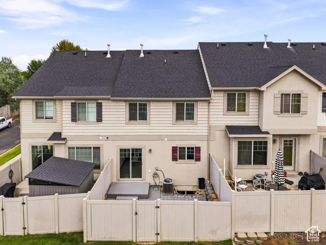 Enclosed rear patio featuring white privacy fencing, a covered storage shed, and a sliding glass door entry