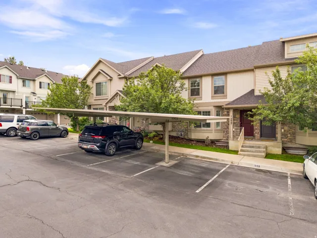 Multi-level townhome with stone accents, covered parking, and mature landscaping