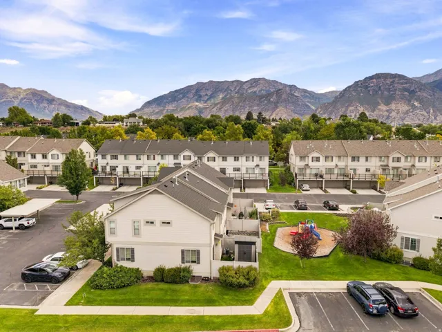 Mountain backdrop, residential community, multiple two-story townhomes, manicured green spaces, and a dedicated play area