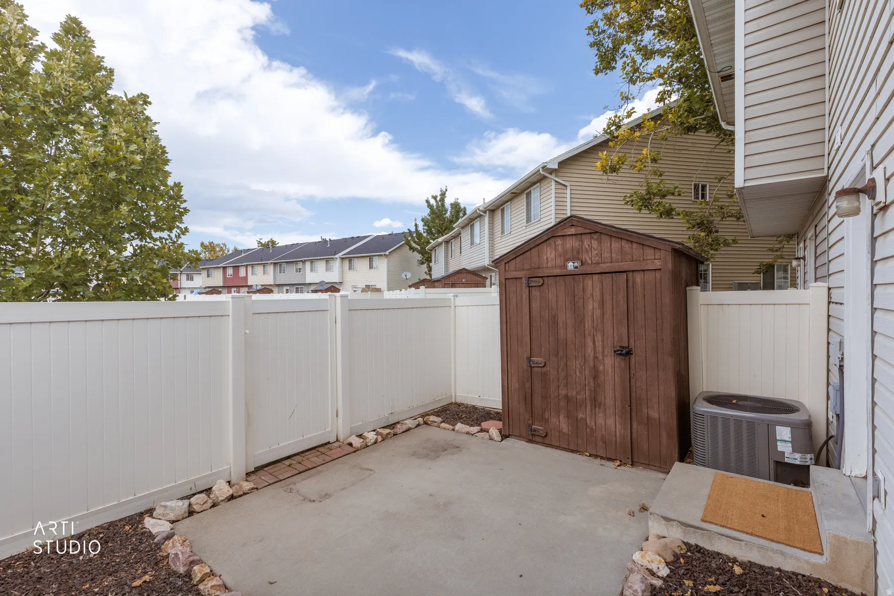 Private patio featuring a white privacy fence and a built-in storage shed