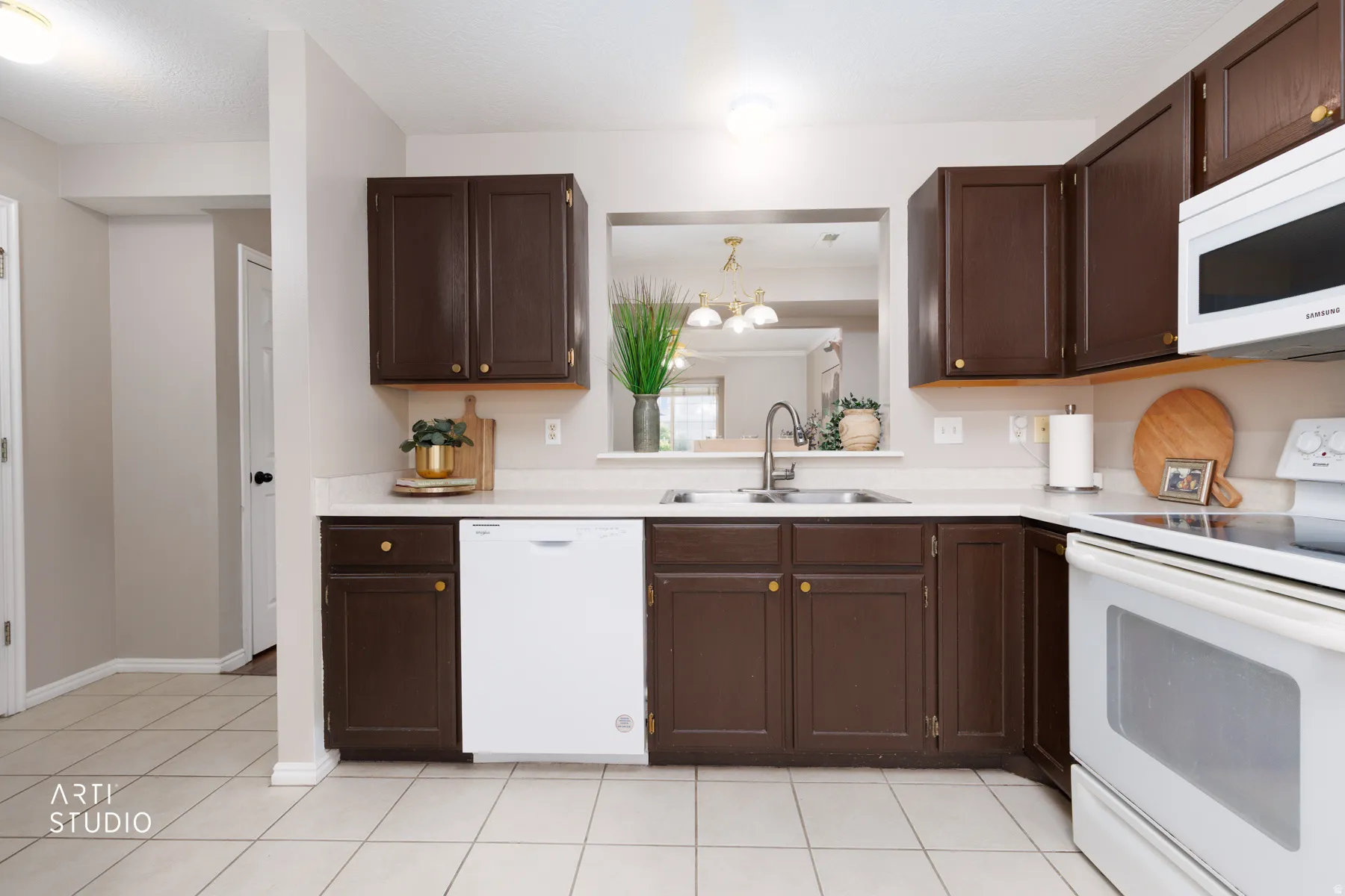 Kitchen featuring dark wood cabinetry, light countertops, stainless steel sink with a gooseneck faucet, white dishwasher, and white tile flooring
