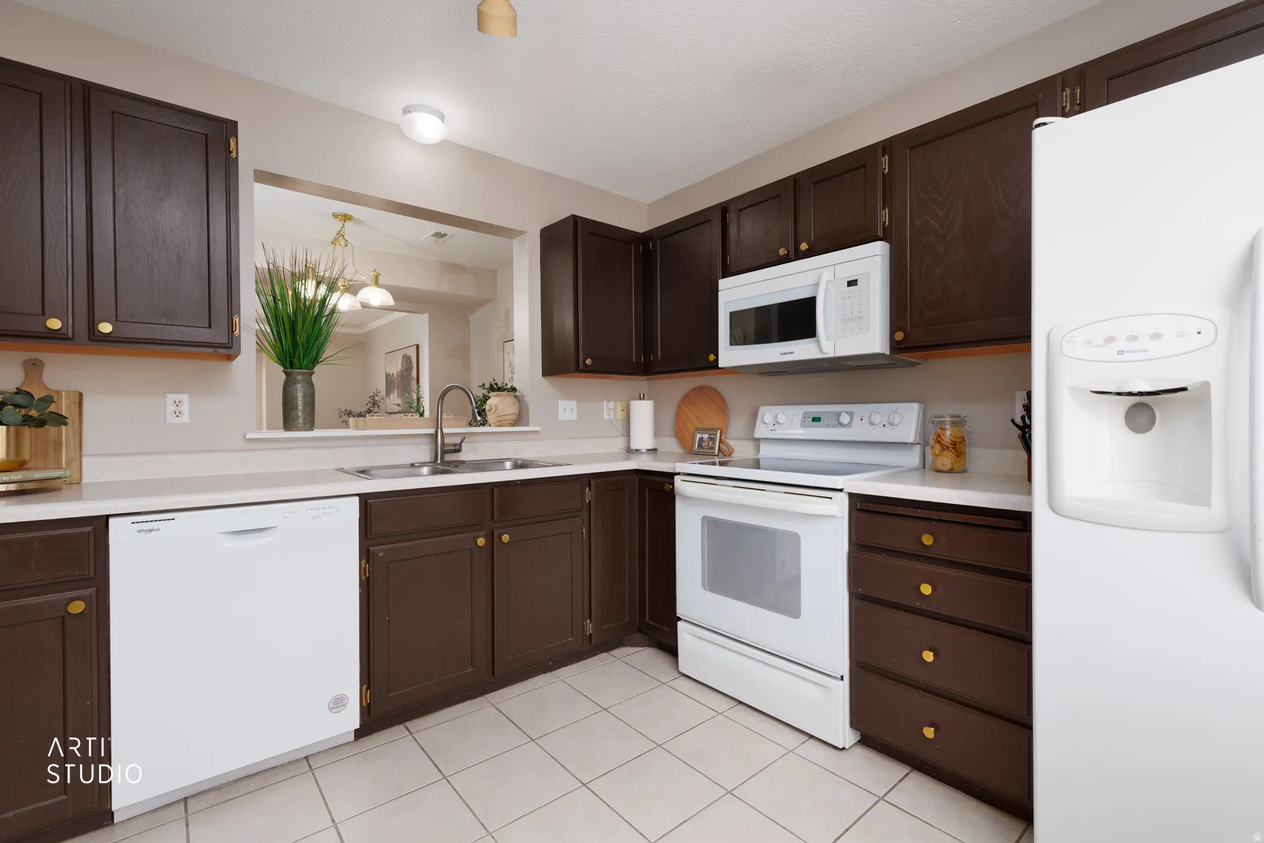 Kitchen featuring wood-finish cabinetry, white appliances, light-toned countertops, and tile flooring