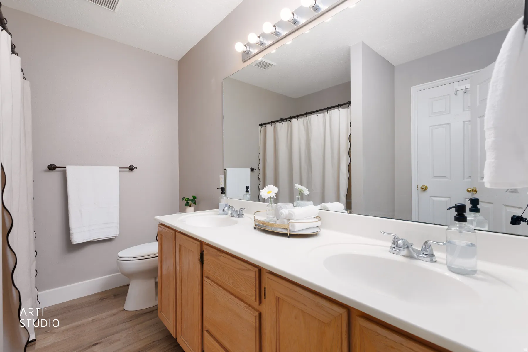 Dual vanity with integrated sinks, wood-finish cabinetry, and a full-width mirror