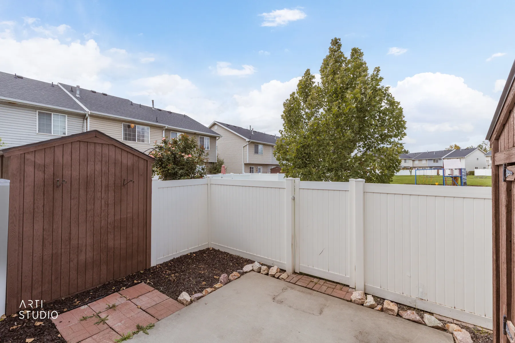 Private patio featuring a concrete slab and a white privacy fence