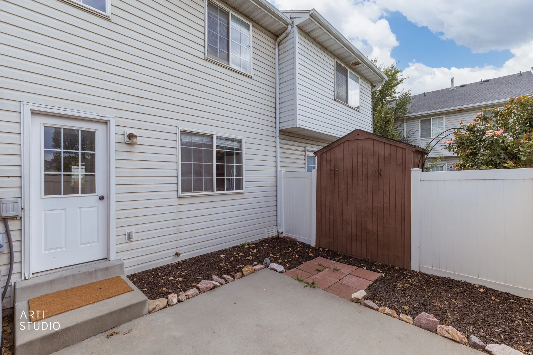 Private patio with concrete surfacing, white vinyl fencing, and a built-in storage shed