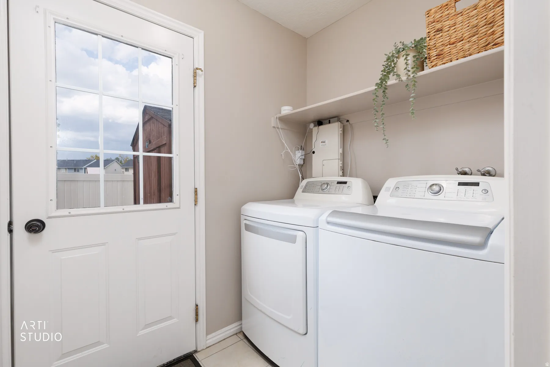 Utility room featuring a white paneled door with windowpanes, light neutral wall paint, and white upper shelving