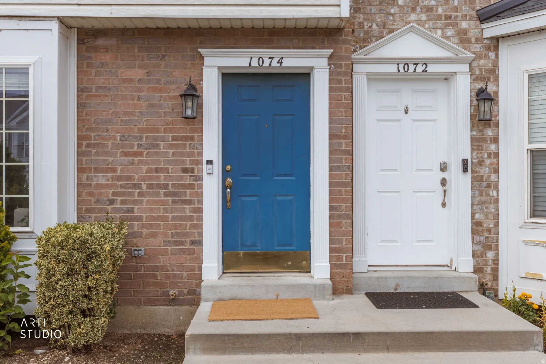 Brick exterior featuring a blue entry door with brass hardware
