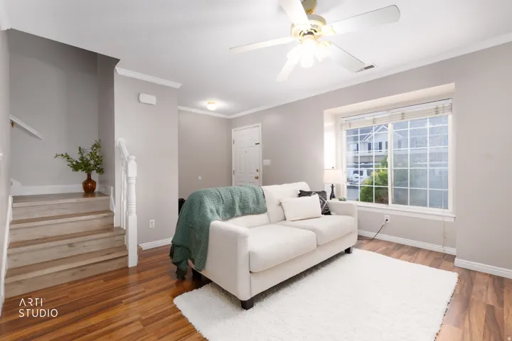 Living area featuring vinyl flooring, a multi-pane window, and a ceiling fan with integrated lighting
