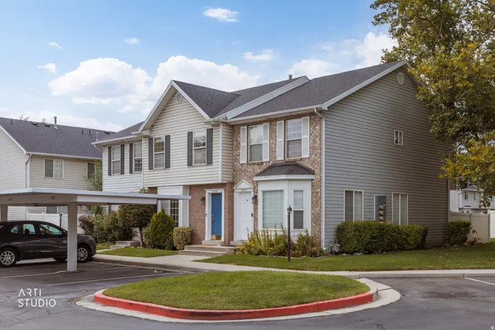 Brick and siding exterior with a covered carport, manicured lawn, and mature landscaping