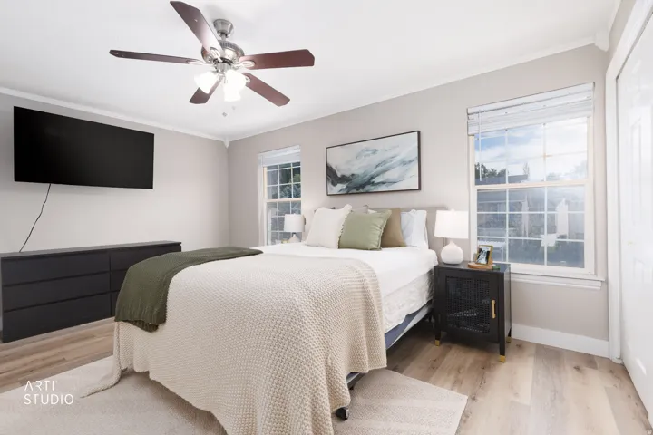 Crown molding, LVP flooring, two large windows, white trim, and a ceiling fan with integrated lighting