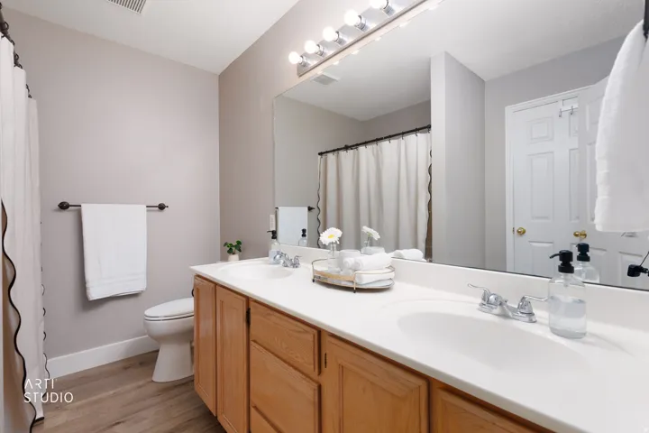 Dual vanity with integrated sinks, wood-finish cabinetry, and a full-width mirror