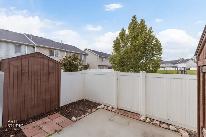 Private patio featuring a concrete slab and a white privacy fence
