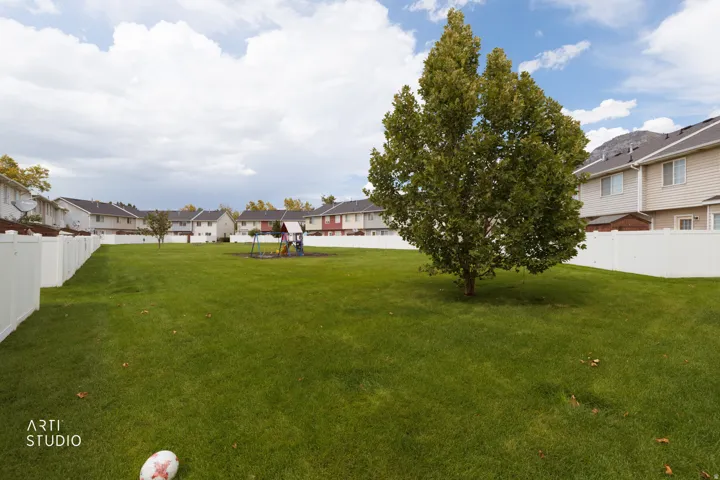 Expansive green lawn with a mature tree and white privacy fencing