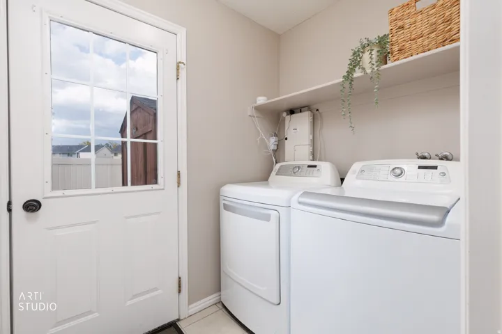 Utility room featuring a white paneled door with windowpanes, light neutral wall paint, and white upper shelving
