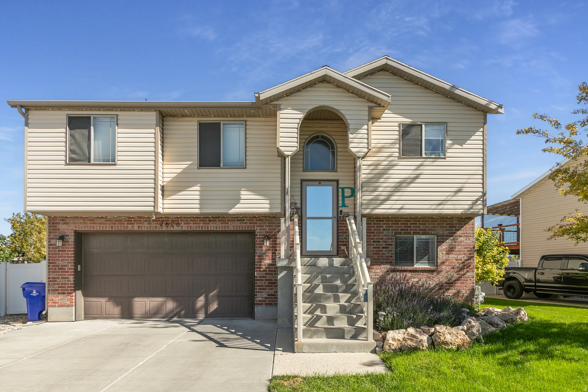 Two-story residence featuring a brick and siding exterior, an arched entryway with an arched window, a two-car garage, and concrete steps leading to the front door