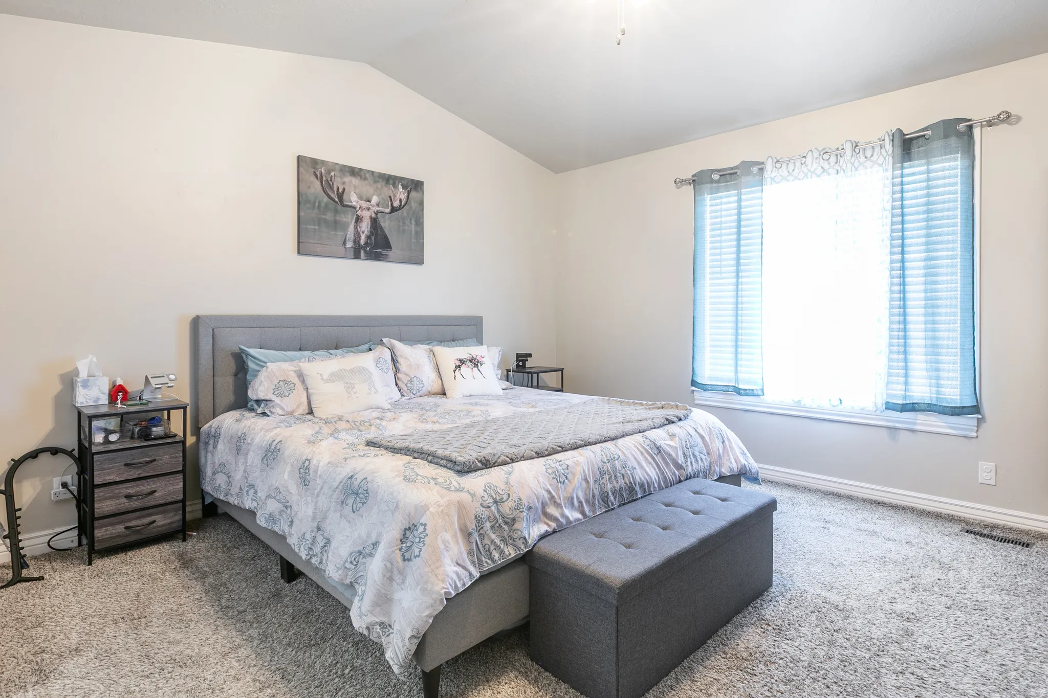 Vaulted ceiling, carpeted flooring, large window, and light-toned walls
