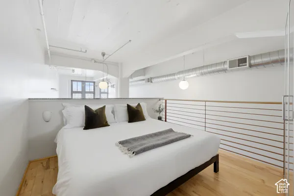 Hardwood flooring, exposed ductwork, white painted wood ceiling, contemporary pendant lighting, and a partial glass partition
