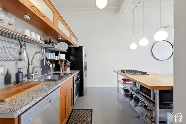 Kitchen featuring light wood-finish cabinetry, granite-style countertops, stainless steel appliances, and a butcher block island with an integrated cooktop