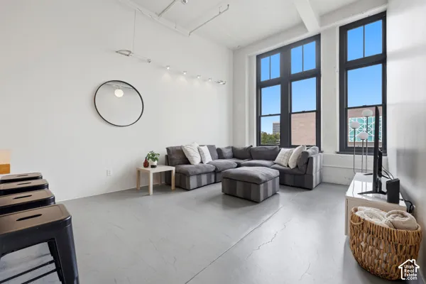 Tall industrial-style windows with dark frames, high ceilings with exposed conduit, and polished concrete flooring