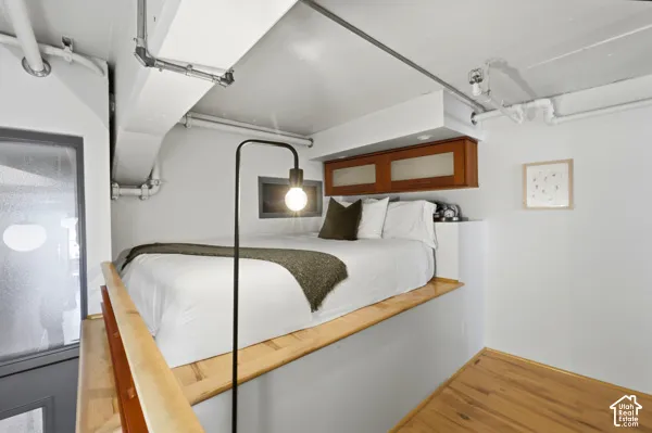 Loft bedroom with wood-finish flooring, built-in cabinetry, and integrated lighting