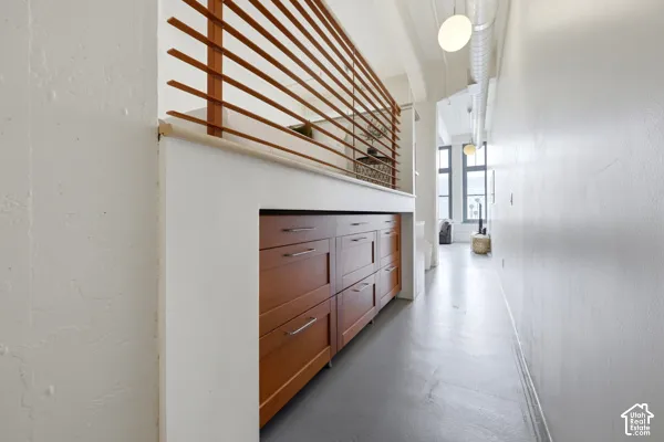 Built-in cabinetry with wood-finish drawers and brushed nickel hardware, open slatted wood railing, exposed ductwork, and suspended globe lighting