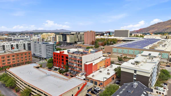 Urban landscape featuring diverse architectural styles, multi-story buildings, and visible mountain backdrop