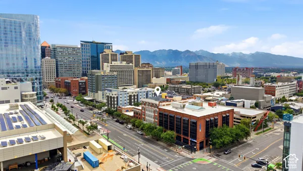 City skyline with high-rise and mid-rise buildings, urban streetscape, and distant mountains