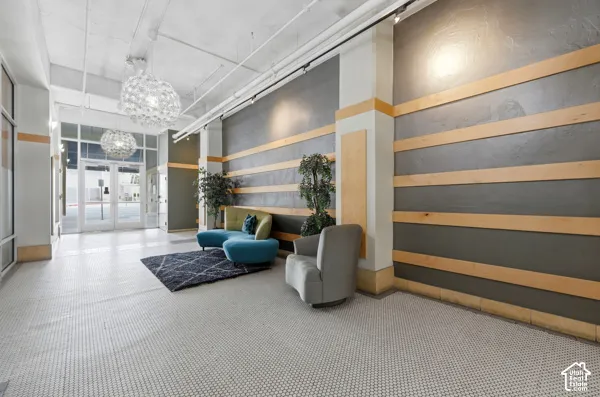 Entryway featuring white hexagonal tile flooring, dual contemporary pendant light fixtures, and a wall with horizontal wood paneling and dark grey finish