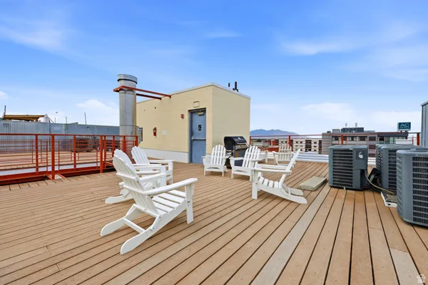 Expansive rooftop deck featuring wood-finish decking, a secure perimeter railing, and a background of distant mountains