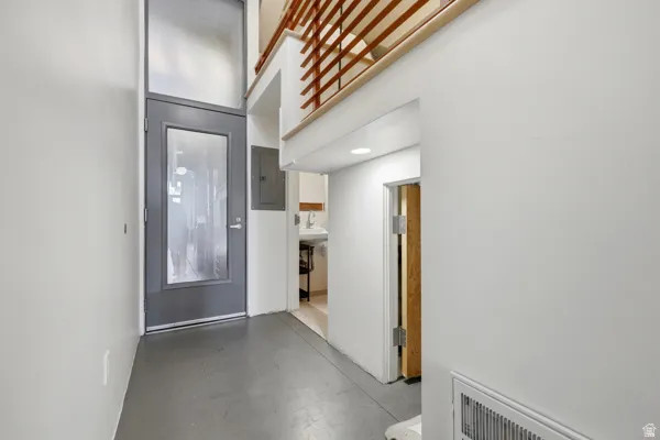 Entryway featuring a full-light door with transom, gray floor, recessed lighting, and a wood-slat railing system