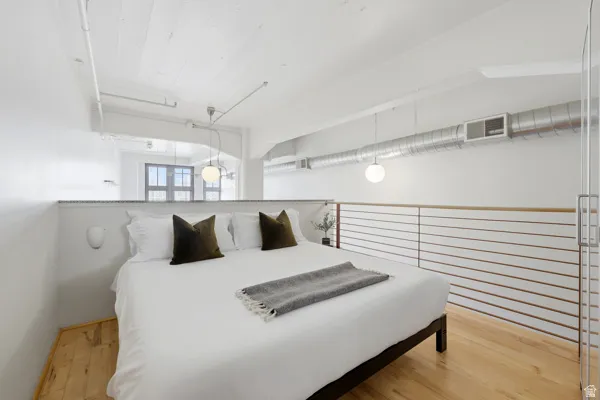 Hardwood flooring, exposed ductwork, white painted wood ceiling, contemporary pendant lighting, and a partial glass partition