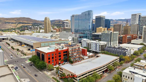 Urban cityscape with a prominent red-brick building featuring multiple windows, surrounded by diverse architectural styles