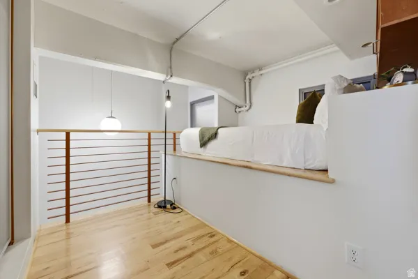 Open-concept room featuring wood-finish flooring, a white accent wall, and a horizontal bar railing