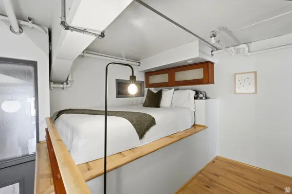Loft bedroom with wood-finish flooring, built-in cabinetry, and integrated lighting