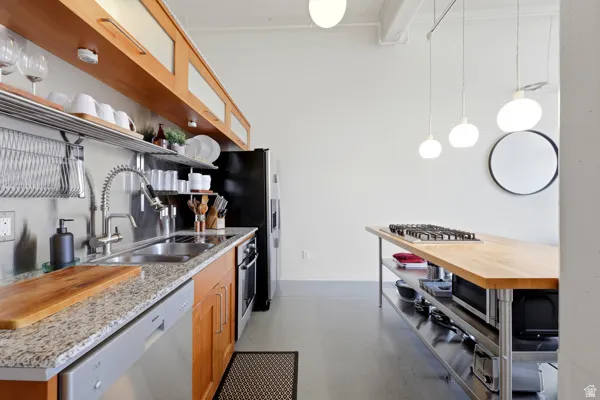 Kitchen featuring light wood-finish cabinetry, granite-style countertops, stainless steel appliances, and a butcher block island with an integrated cooktop