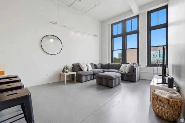 Tall industrial-style windows with dark frames, high ceilings with exposed conduit, and polished concrete flooring