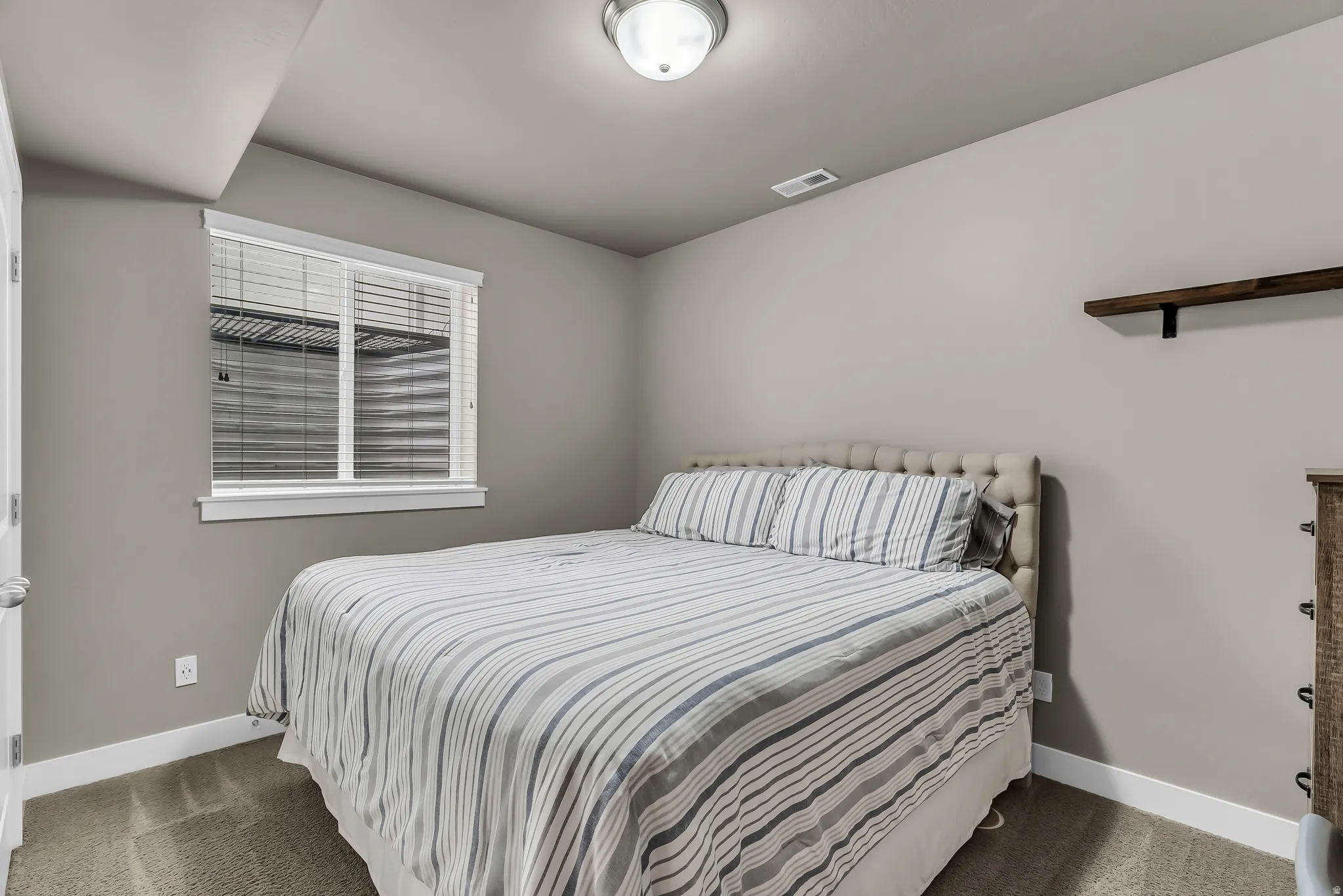 Carpeted flooring, recessed ceiling light, built-in wall shelf, and window with blinds