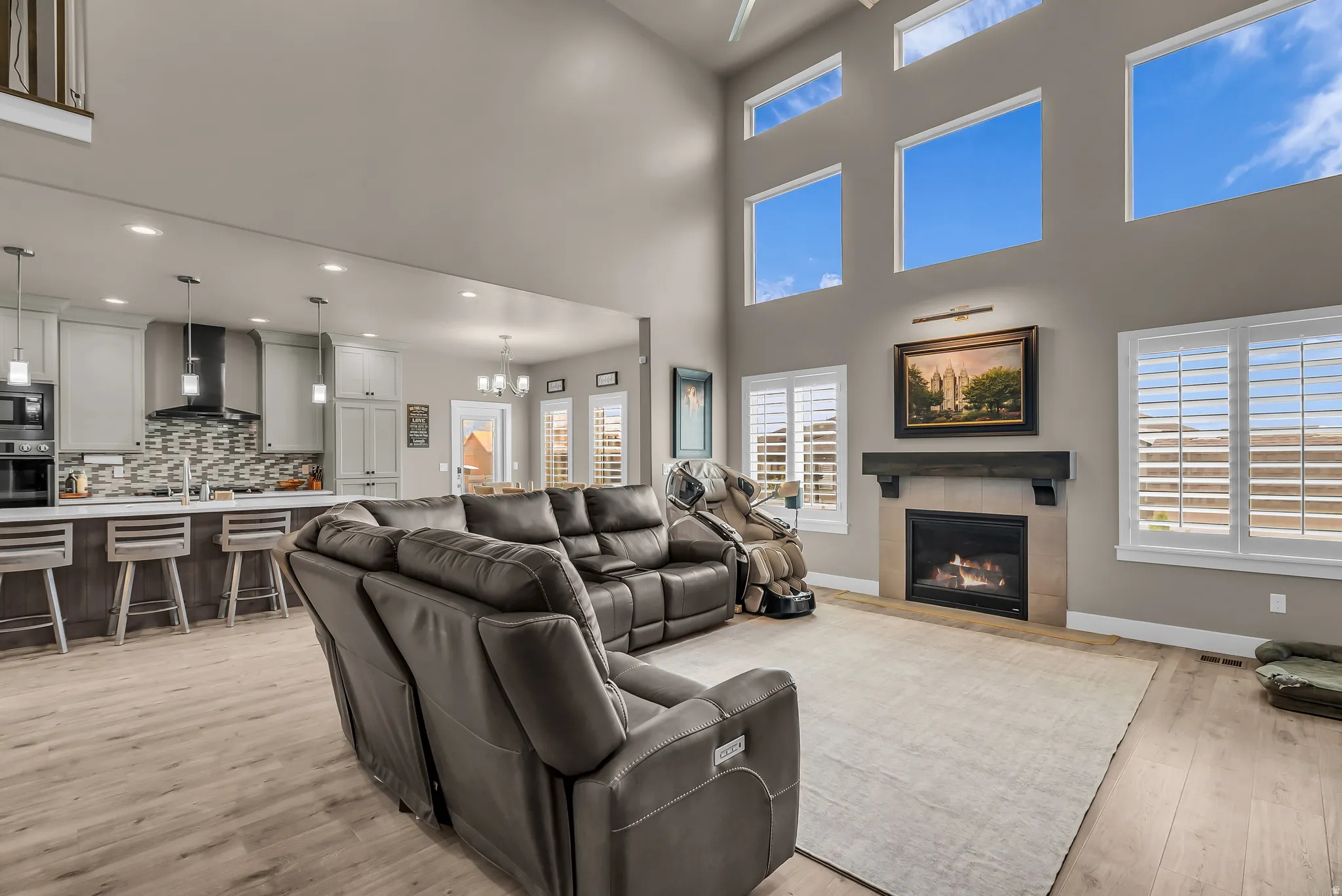 Two-story living area with a gas fireplace, built-in mantel, and light wood-finish flooring