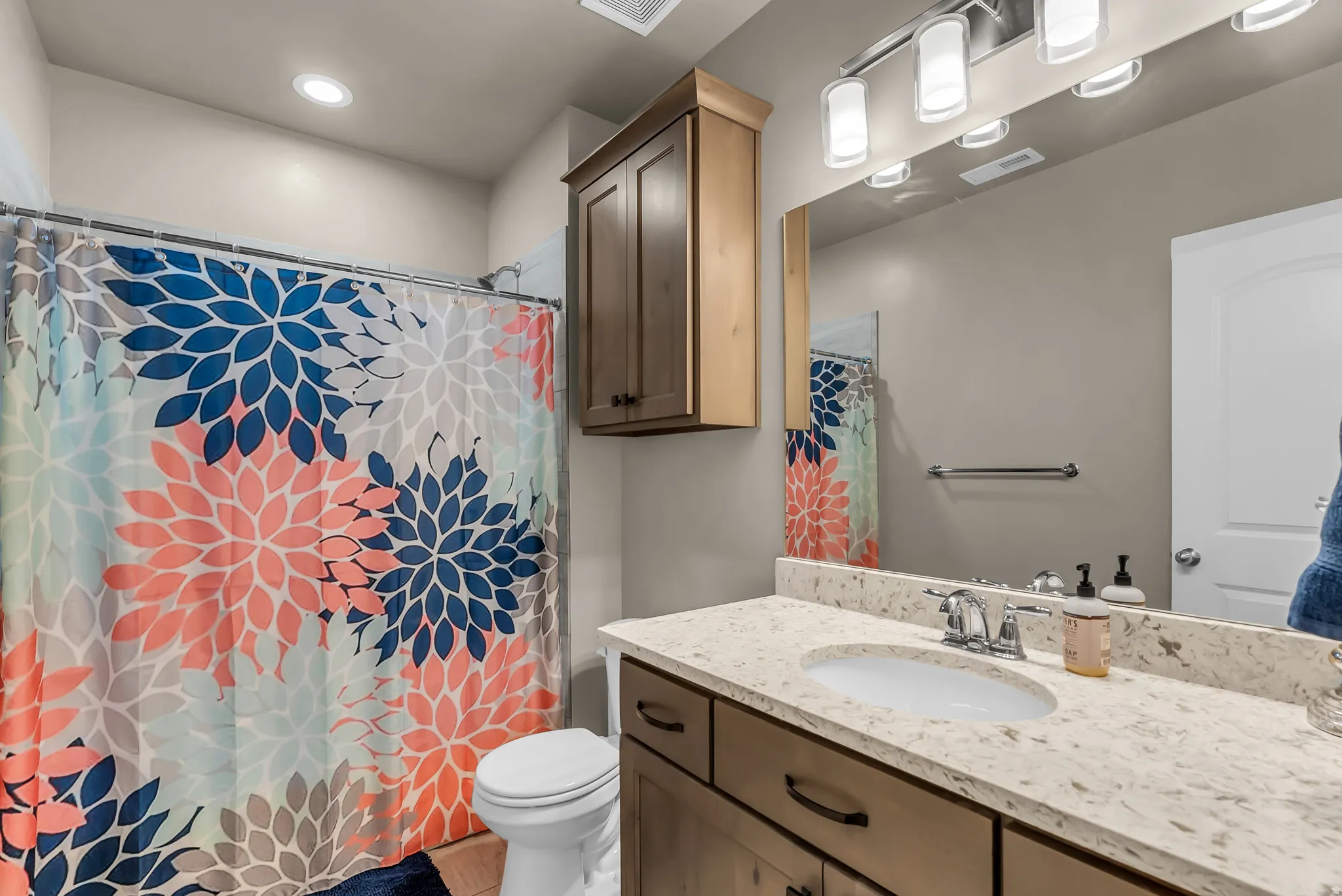 Bathroom with a vanity featuring a light-toned countertop, an undermount sink, and wood-finish cabinetry