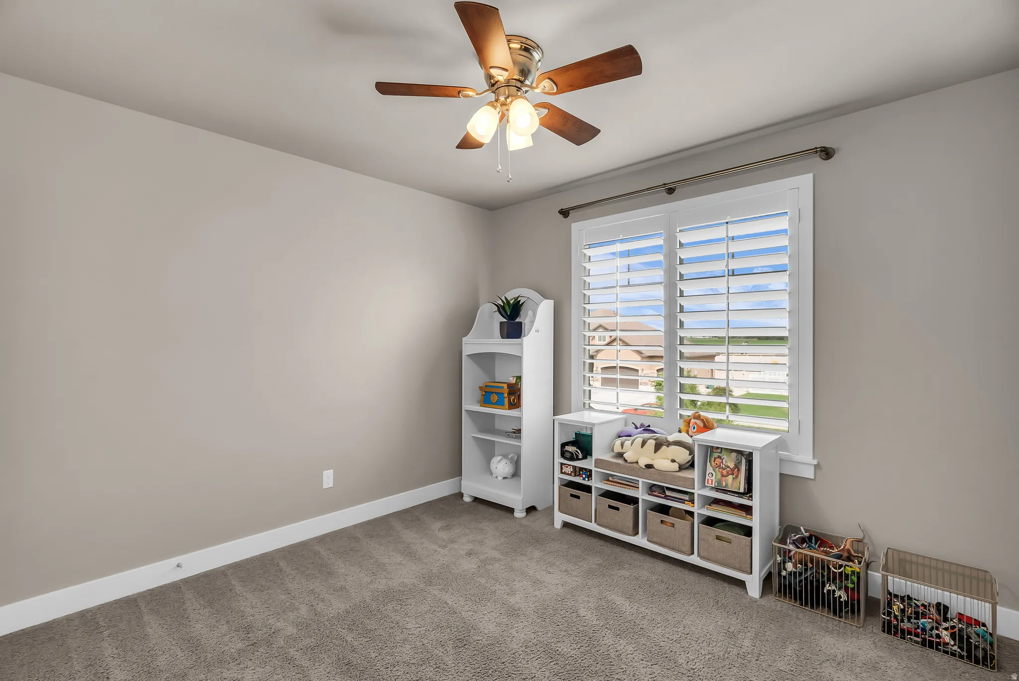 Neutral paint palette with ceiling fan light fixture, carpet flooring, and window with plantation shutters