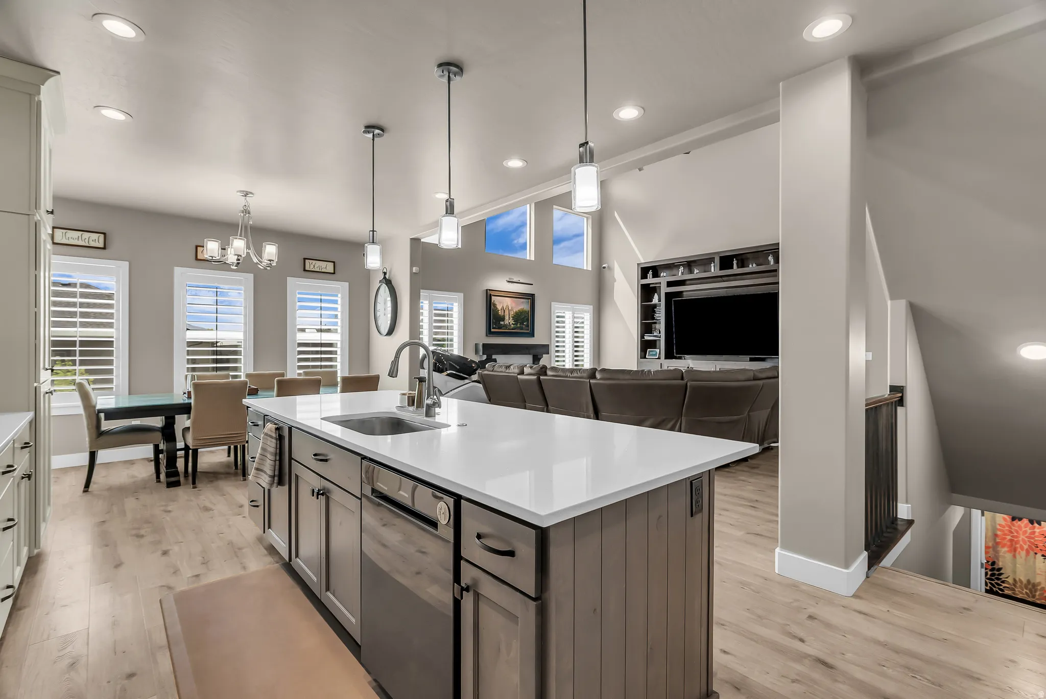 Open concept living space featuring a central island with sink, stainless steel appliances, and wood-finish flooring