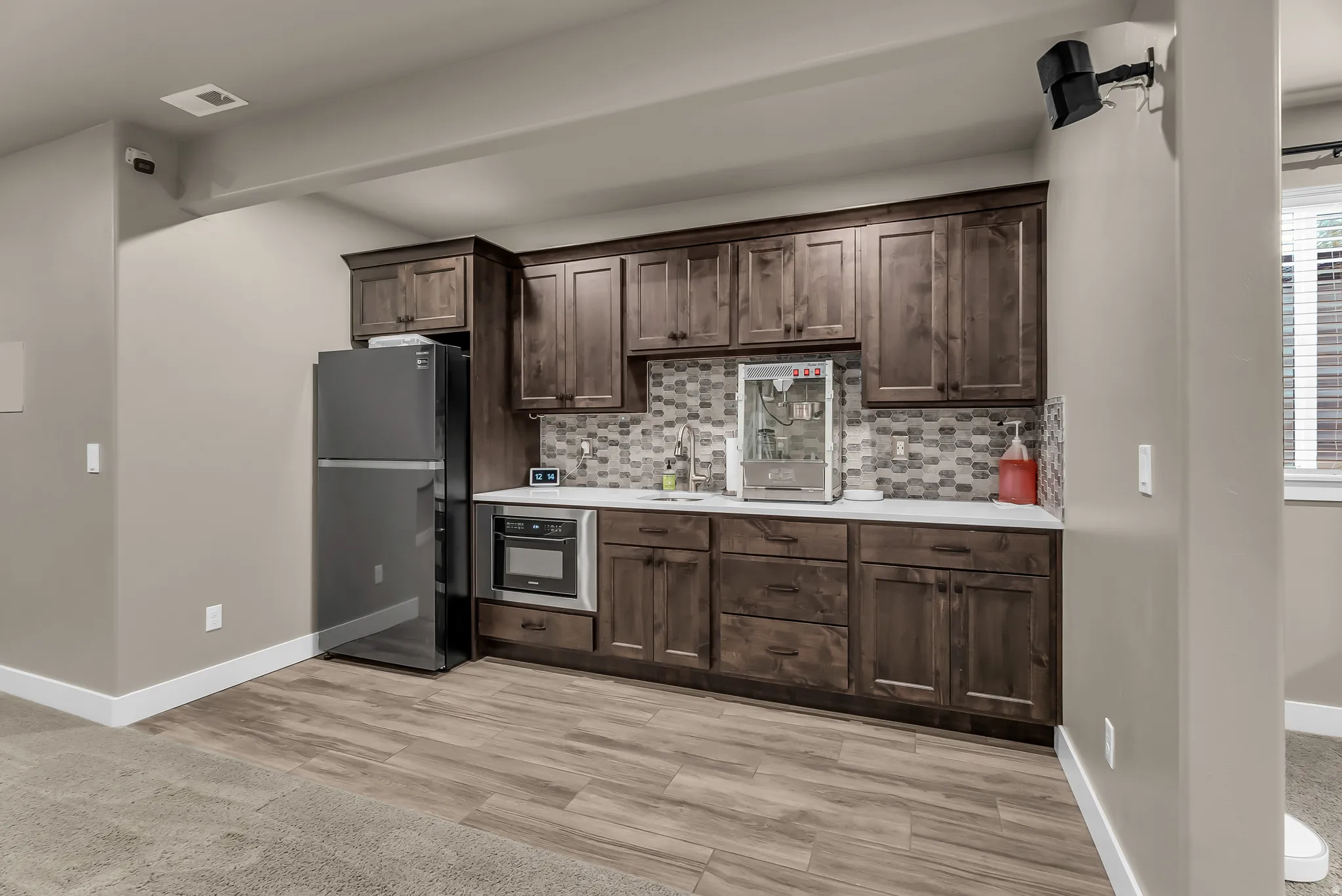 Built-in cabinetry with dark wood finish, white countertop, tile backsplash, and integrated stainless steel appliances