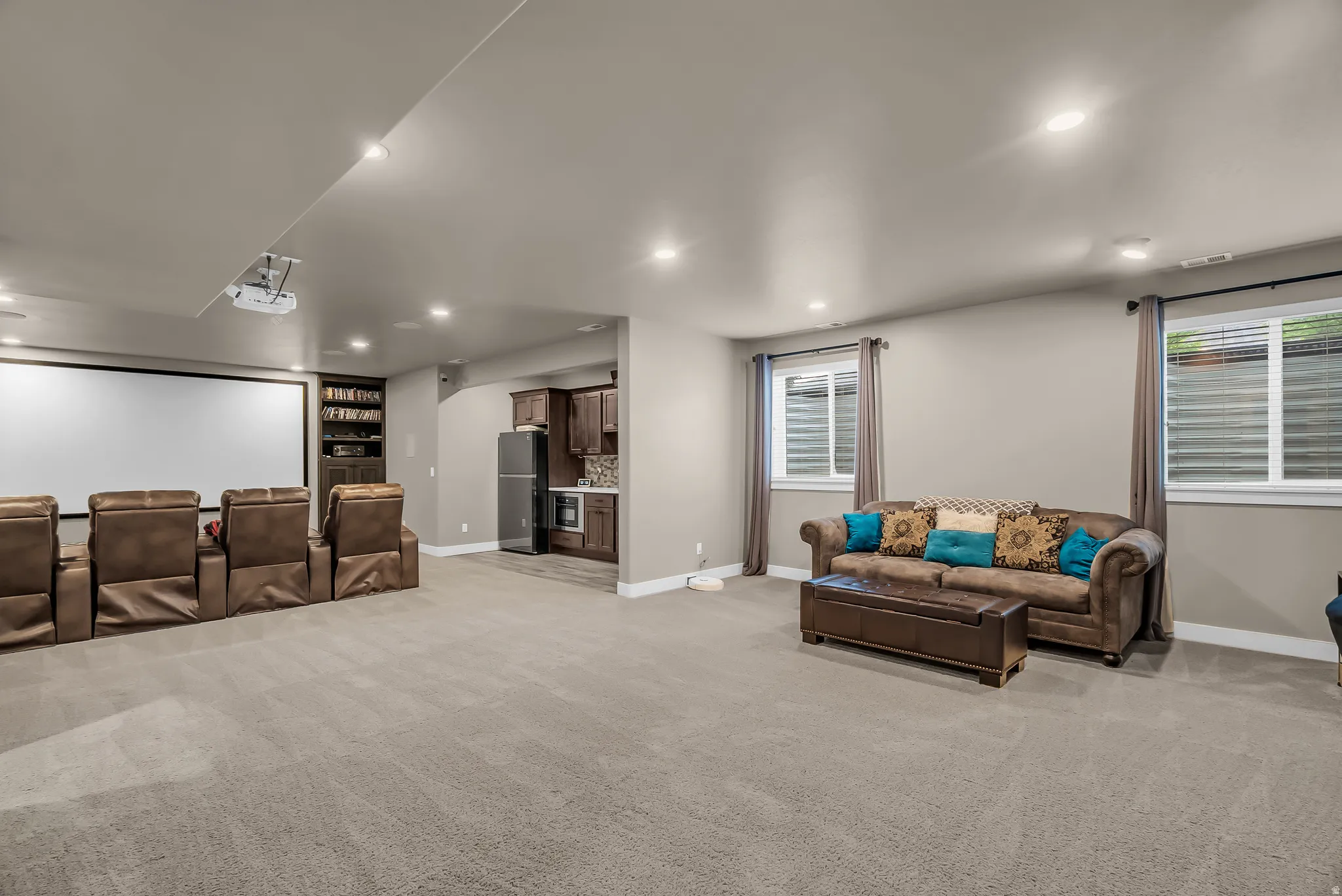 Expansive carpeted area featuring recessed lighting, a built-in media center, and a wet bar with cabinetry and tile backsplash