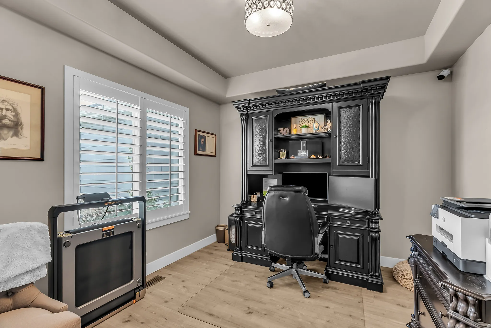Tray ceiling with recessed lighting, wood-finish flooring, plantation shutters, and a built-in desk with shelving