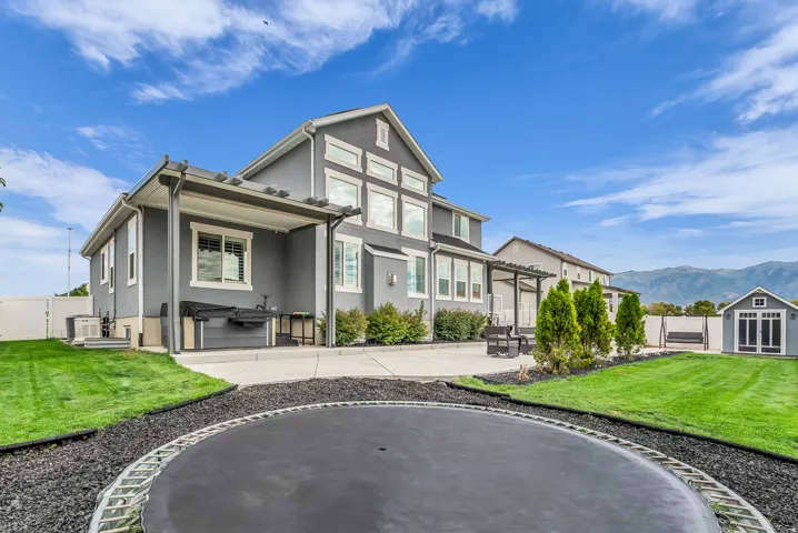 Modern farmhouse exterior with board-and-batten siding and gabled roofline, featuring a covered front porch, multi-pane windows, and professional landscaping with manicured lawn, mature evergreen plantings, and decorative stone edging