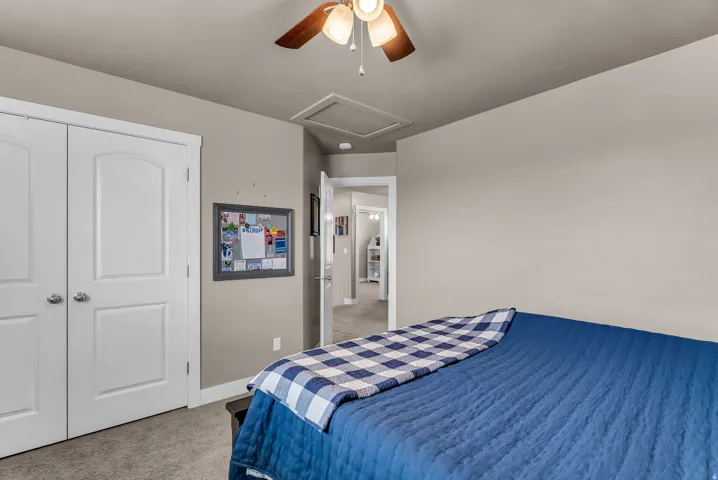 Carpeted flooring, white bi-fold doors, and a ceiling fan with integrated lighting
