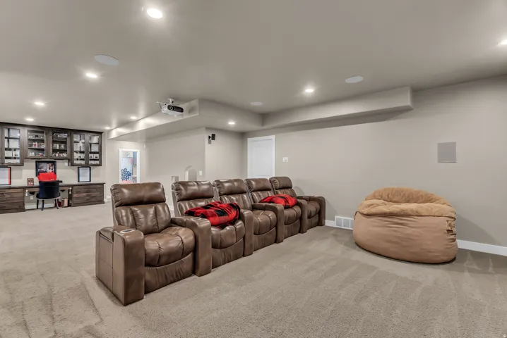Recessed lighting illuminates a spacious room with light-toned carpeting and neutral wall paint