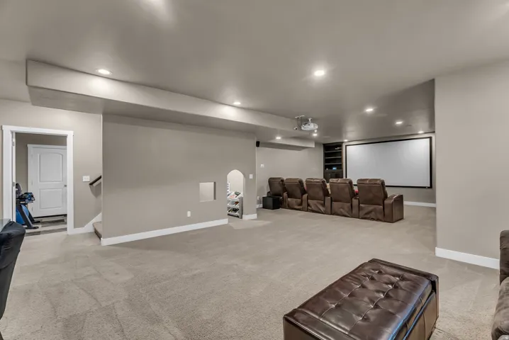 Entertainment space featuring a large projection screen, recessed lighting, built-in shelving, and neutral carpeting