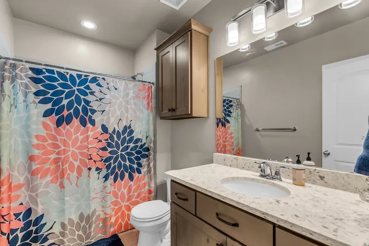 Bathroom with a vanity featuring a light-toned countertop, an undermount sink, and wood-finish cabinetry