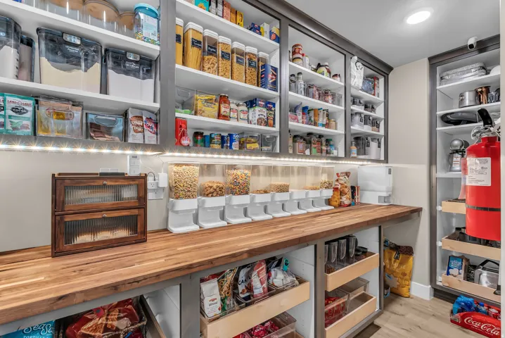Built-in pantry shelving featuring under-cabinet lighting, a substantial wood-finish countertop, and pull-out drawers